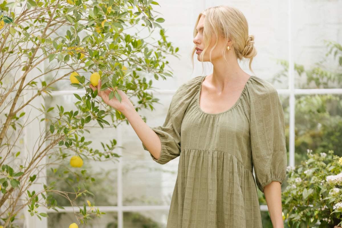 Gentle Gawn Focus Banner of a woman wearing Gentle Fawn and picking a lemon from a lemon tree.