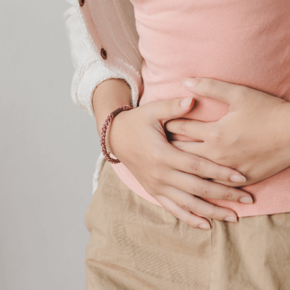 A woman reacting to bloat in perimenopause by holding her belly with her hands.