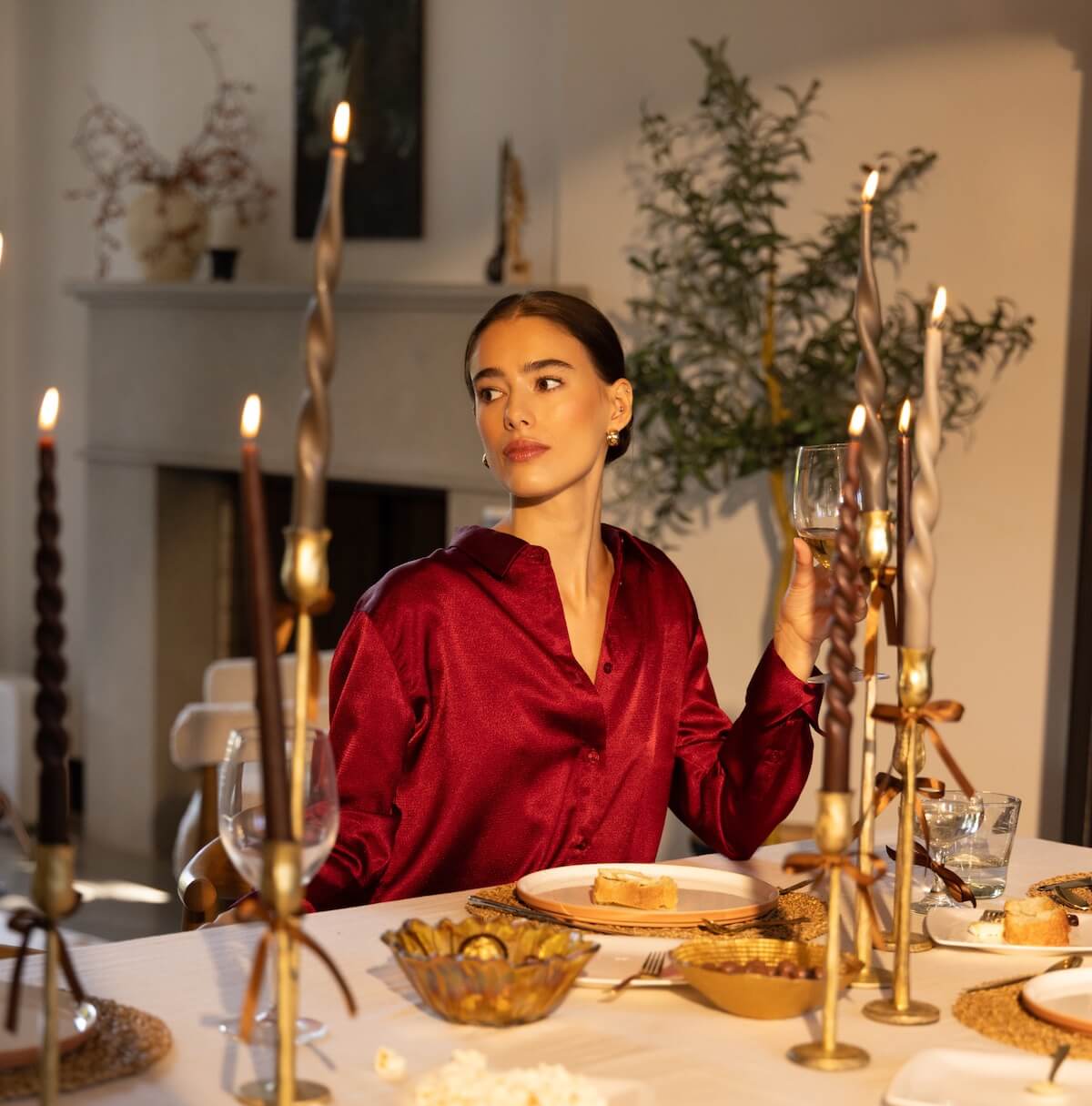 Woman wearing the Gentle Fawn Simone Blouse in deep red, seated at a candlelit fall dinner table — available at Lemonberry Boutique.