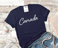Flat lay of the blue Canada Tee paired with denim shorts and sandals.