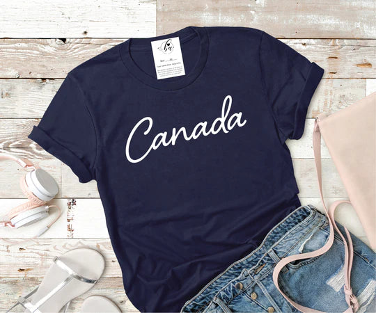 Flat lay of the blue Canada Tee paired with denim shorts and sandals.