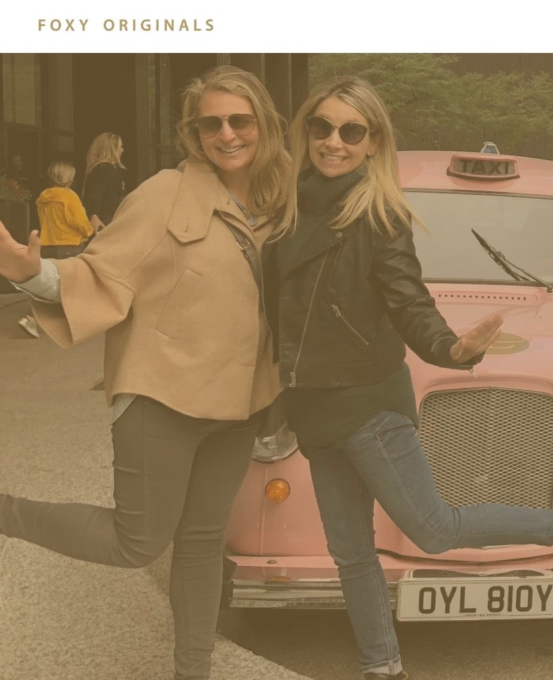 Jen and Suzie from Foxy Originals standing in front of a pink cab abroad