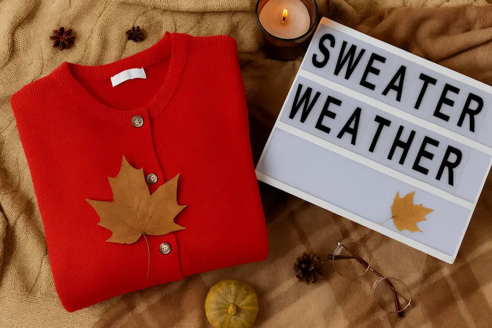 Sweater Weather title image with a red sweater on a brown surface beside a sign.