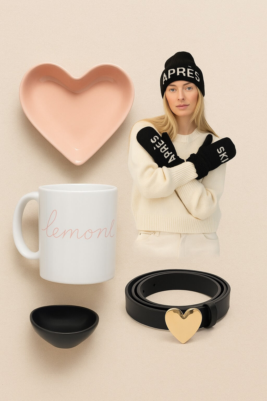 Minimalist winter lifestyle flat lay featuring a Lemonberry mug, pink heart-shaped bowl, black Apres beanie and mittens, and black belt with gold heart buckle — styled on a soft neutral background with cozy, understated vibes.