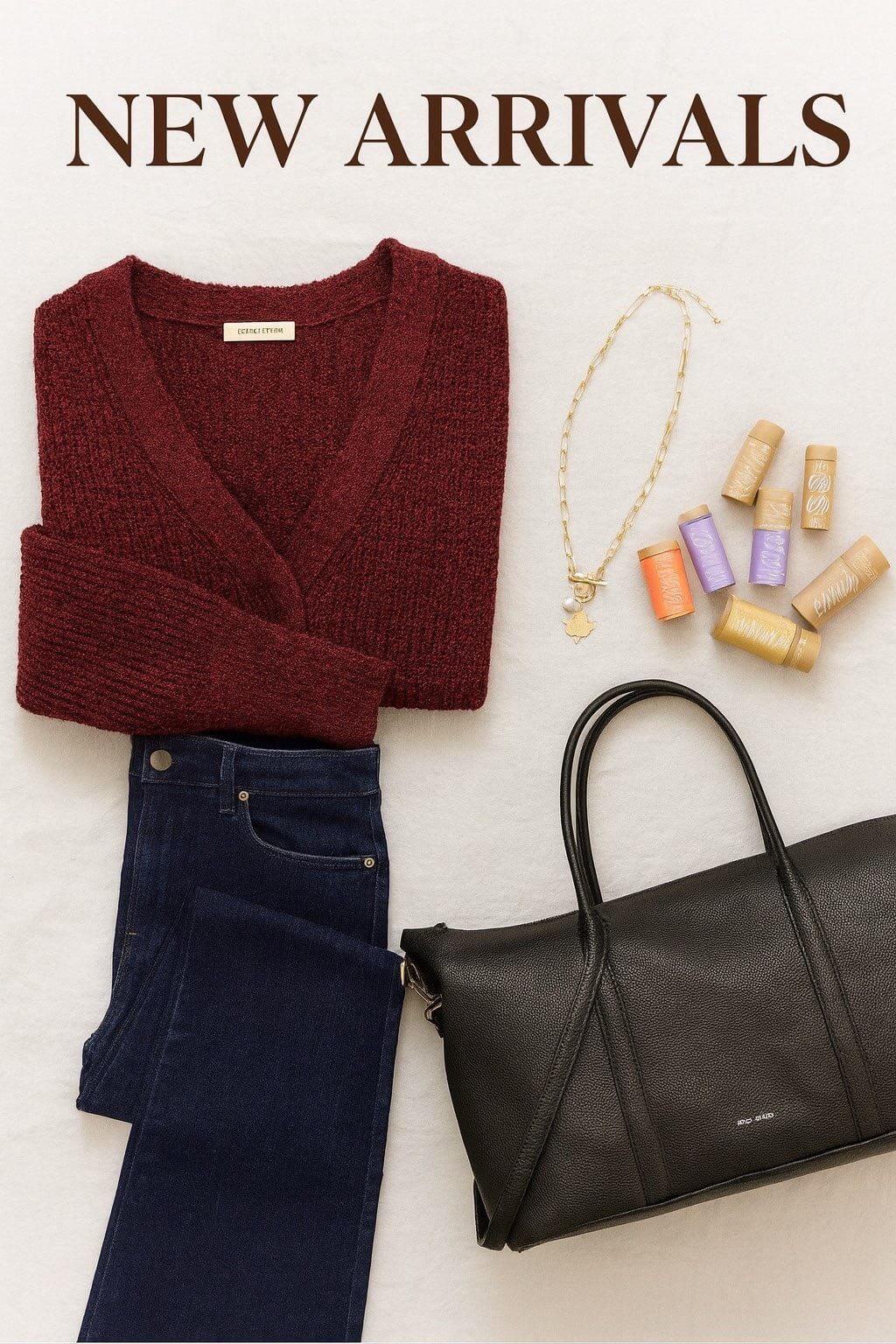 Fall new arrivals flat lay featuring a red Gentle Fawn sweater, dark denim jeans, gold Foxy Originals maple leaf necklace, Pixie Mood black vegan weekender bag, and Chubby lip balms — styled on a soft neutral background at Lemonberry Boutique.