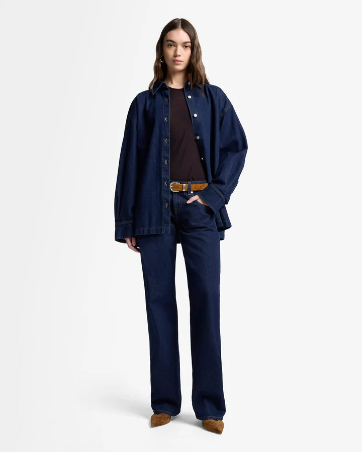 Person wearing a navy blue denim jacket and pants on a white background