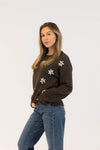 Side angle of Aiden Daisy sweater in brown with embroidered white daisies, paired with blue jeans – Lemonberry boutique
