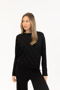 Woman wearing a black long-sleeve top with white polka dots on a white background