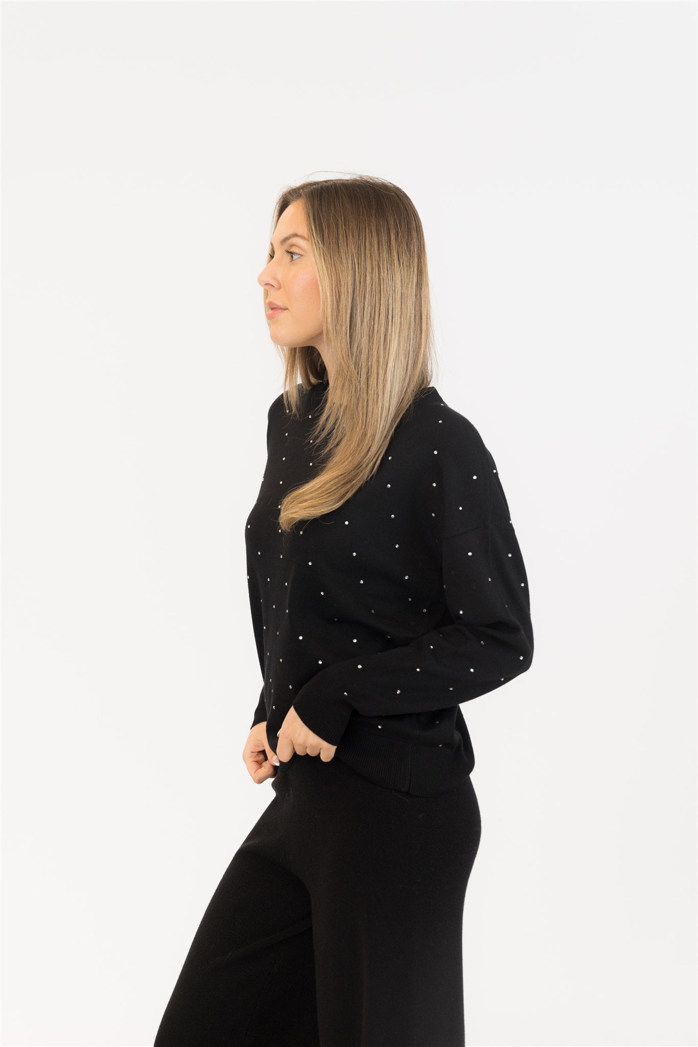 Woman wearing a black sweater with white polka dots on a white background