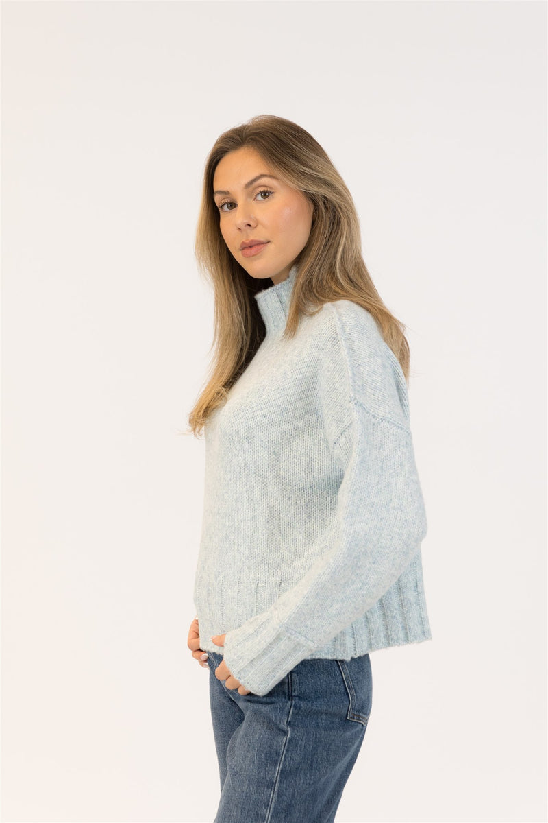 Woman wearing a light blue sweater and jeans on a white background