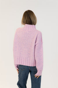 Person wearing a pink sweater and blue jeans on a light background