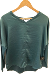 Green blouse on a wooden hanger against a white background inside Lemonberry