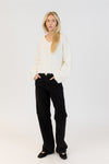 Woman wearing a white sweater and black pants on a white background