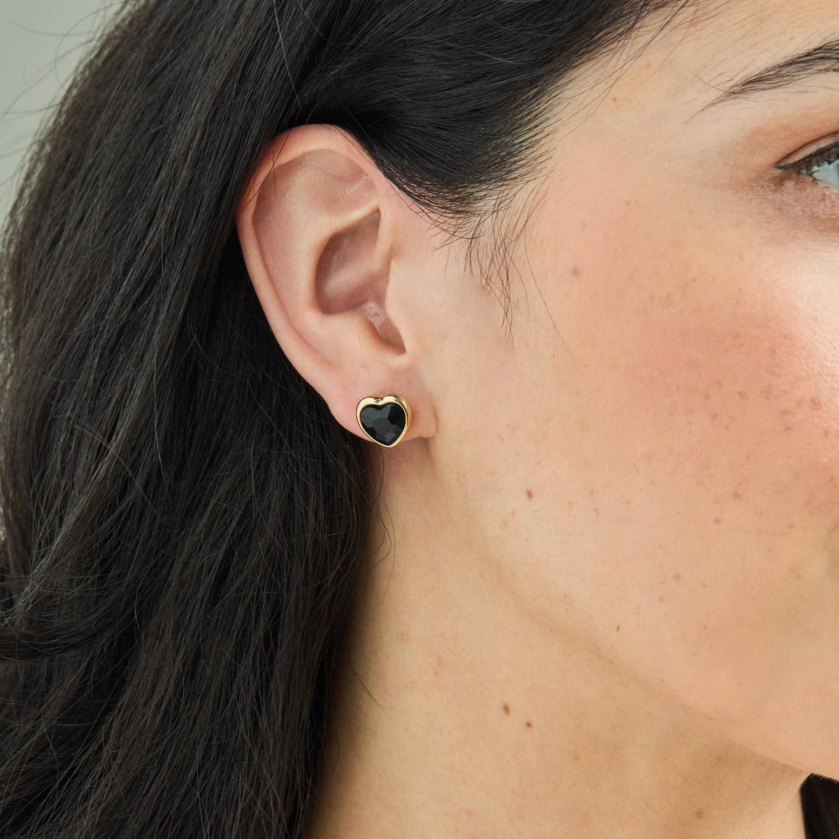 A model wearing the Foxy Originals Freya Earrings in Black, featuring heart-shaped stones and a delicate silver or gold-plated finish. Handmade in Canada by a woman-run brand.