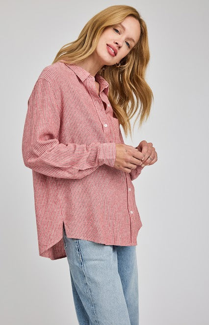 Woman wearing a Garnet striped button-down shirt by Gentle Fawn and blue jeans on a light gray background