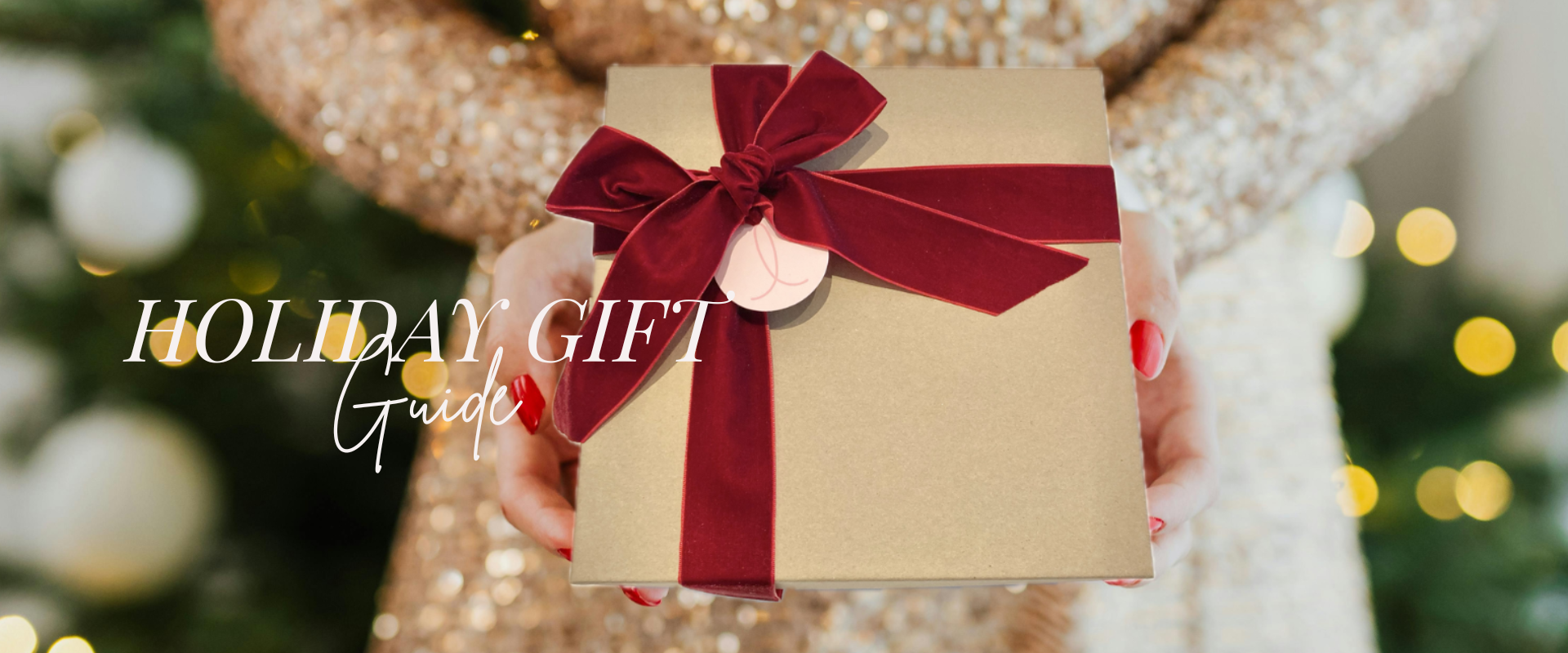 Gold gift box with a red ribbon held by a person against a festive background.