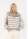 Model in zip-up grey and white striped sweater styled with cream pants against white background