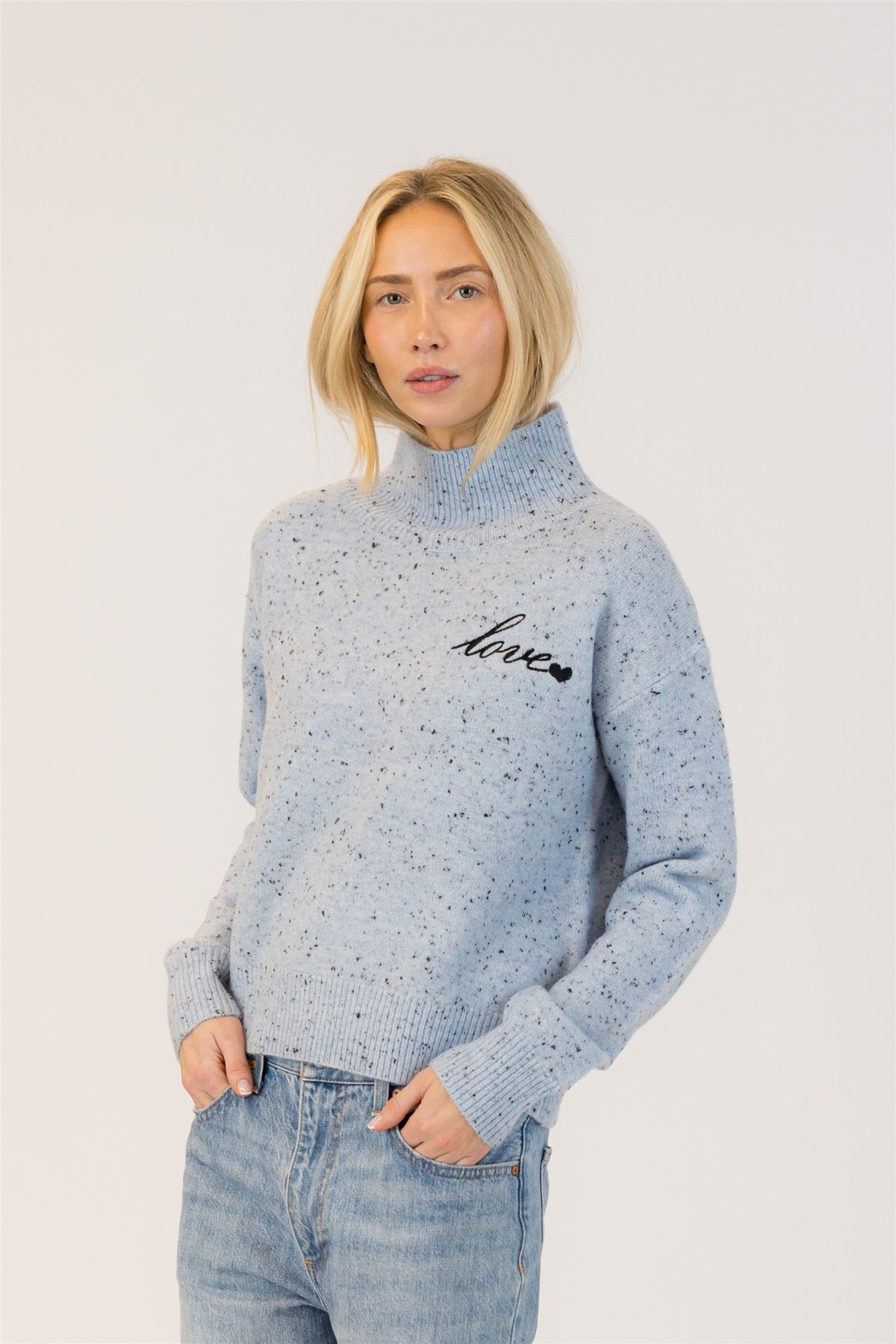 Woman wearing light blue Macy Fleck sweater by Lyla & Luxe with 'love' print on a white background