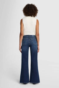 Model wearing 7 For All Mankind Lotta High-Waist Flare Jeans in Dark Blue, back view.