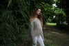 Model standing at an angle in a linen-colored waffle-knit sweater and white leggings, showing off the relaxed drape. Available at Lemonberry, Aurora, ON.