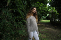 Model standing at an angle in a linen-colored waffle-knit sweater and white leggings, showing off the relaxed drape. Available at Lemonberry, Aurora, ON.