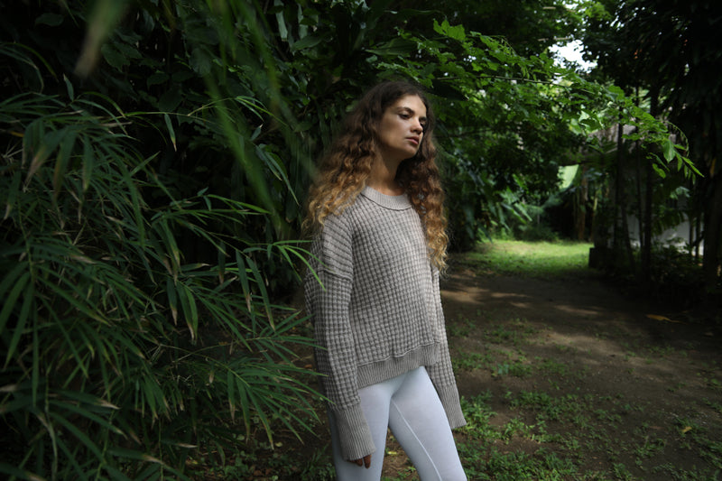 Model standing at an angle in a linen-colored waffle-knit sweater and white leggings, showing off the relaxed drape. Available at Lemonberry, Aurora, ON.
