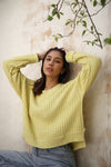 A yellow waffle-knit sweater by Echo Verde, close up, paired with denim jeans.