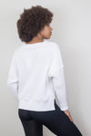 Back view of a white waffle-knit sweater with black leggings, showcasing the slightly longer hem and relaxed silhouette. Available at Lemonberry, Aurora, ON.