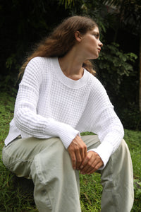 Model sitting down in a white waffle-knit sweater and baggy pants, highlighting the softness and comfortable fit. Available at Lemonberry, Aurora, ON.