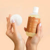Model holding Bkind's nail polish remover in one have with a cotton applicator pad in the other.