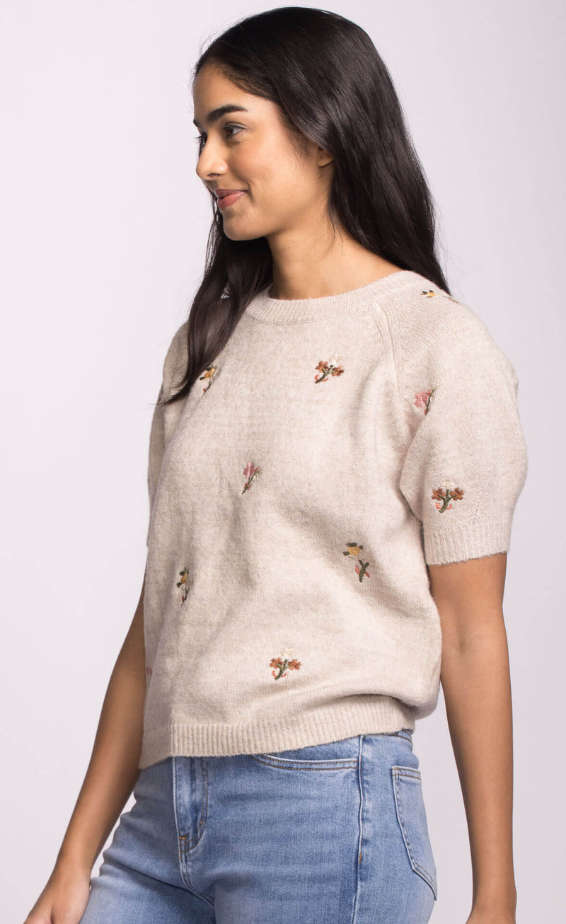 Side view of Alva Sweater by Pink Martini, short sleeve neutral knit with whimsical floral embroidery.
