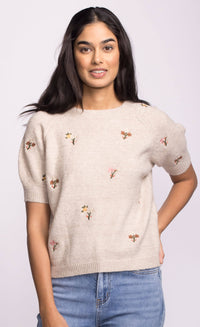 Model wearing the Alva Sweater by Pink Martini, beige knit with delicate floral embroidery on the front.