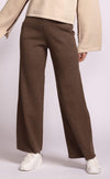 Brown wide-leg Ashley Pants by Pink Martini, worn with a beige jacket and white shoes on a light gray background