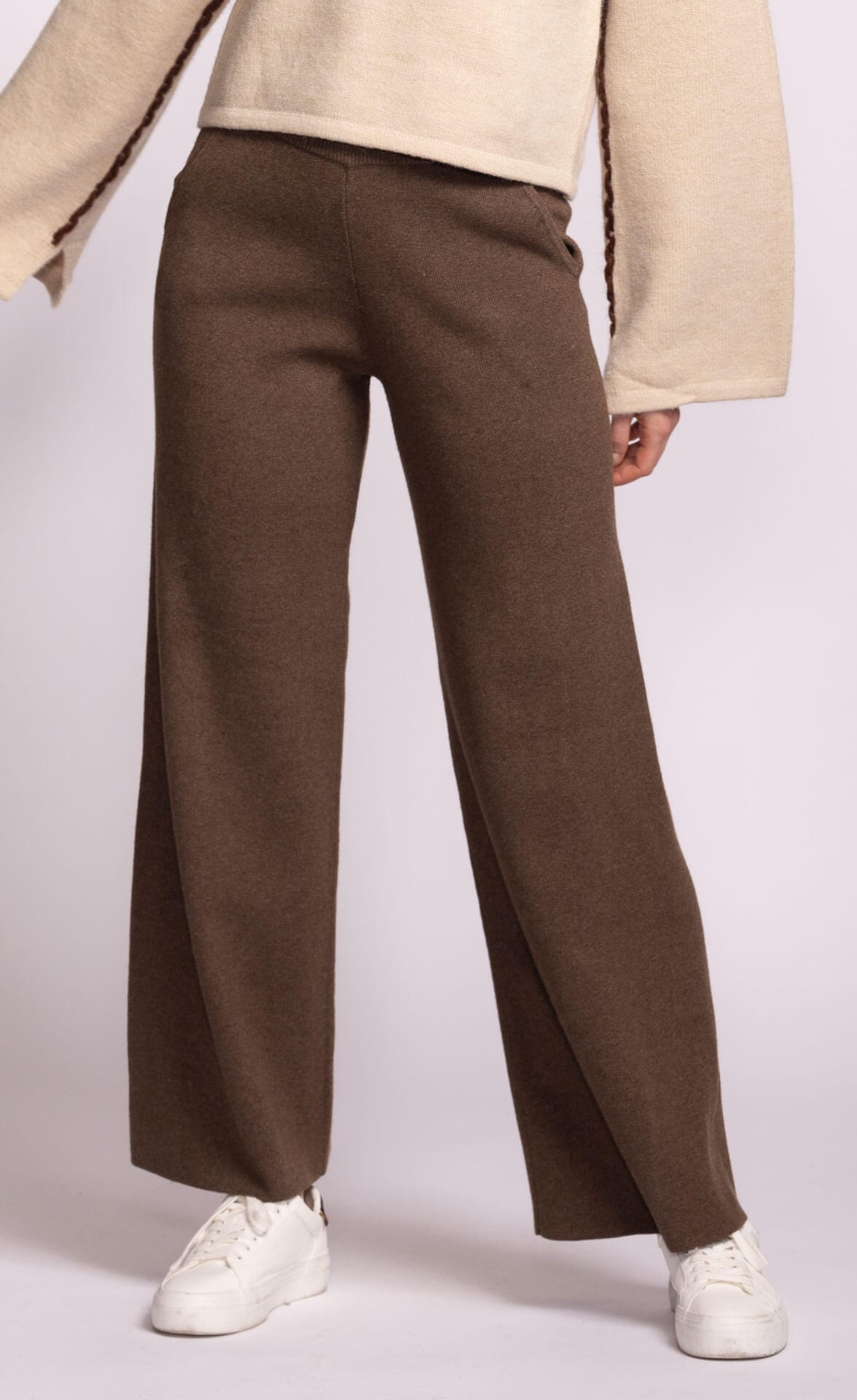 Brown wide-leg Ashley Pants by Pink Martini, worn with a beige jacket and white shoes on a light gray background