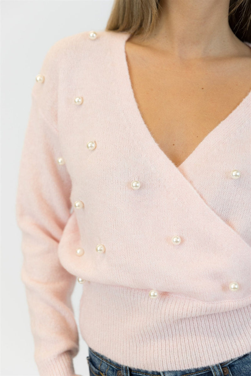 Light pink sweater with pearl embellishments on a plain background