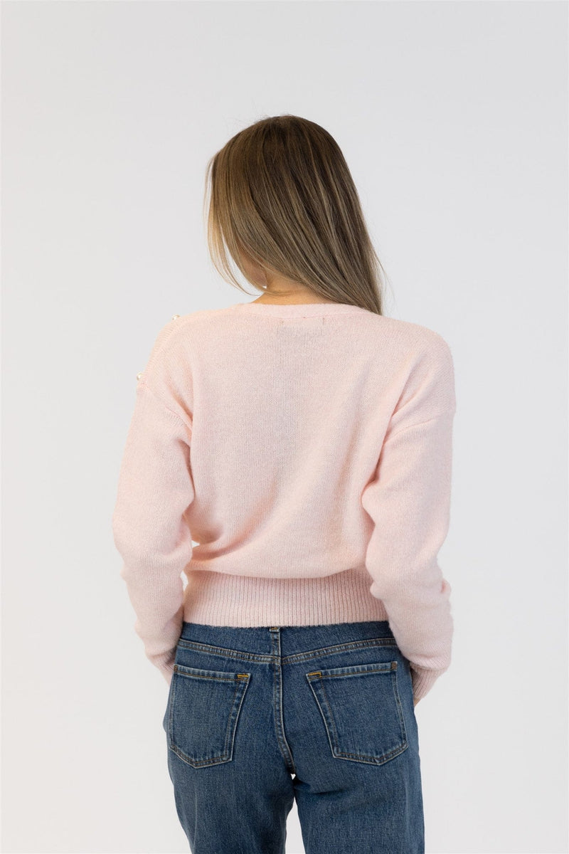 Person wearing a light pink sweater and blue jeans on a white background