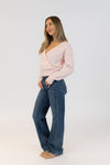 Woman wearing a light pink sweater and blue jeans on a white background