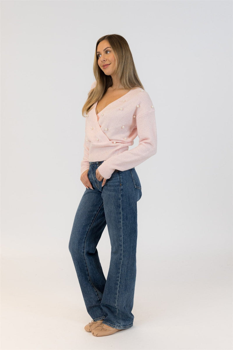 Woman wearing a light pink sweater and blue jeans on a white background