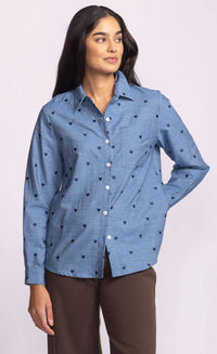 Side view of Azula Top – Pink Martini blue cotton shirt with embroidered hearts, styled with brown pants, photographed at Lemonberry