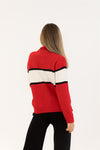 Red sweater with black and white stripes worn by a person on a white background