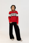 Person wearing a red sweater with 'APRÉS' text, black pants, and headphones on a white background
