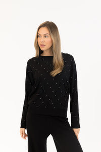 Woman wearing a black long-sleeve top with white polka dots on a white background