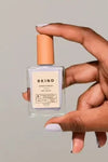Model holding a bottle of Bkind's Run the World colour Nail Polish.