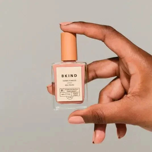 Model holding a bottle of Bkind's Dejavu Nail Polish.