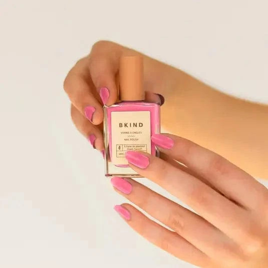 Model holding and displaying Bkind's pink Nail Polish.