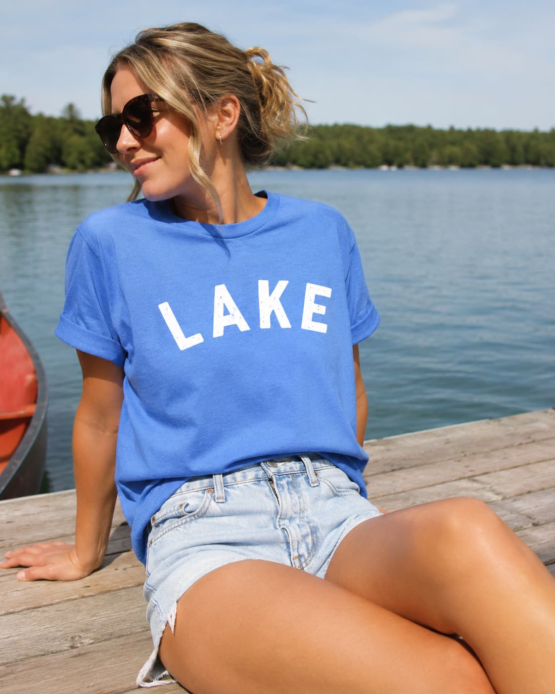 Woman wearing a blue 'LAKE' t-shirt by a lakeside