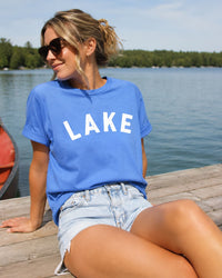 Woman wearing a blue 'LAKE' t-shirt by a lakeside