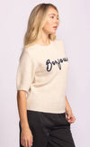 Side view of beige Pink Martini Bonjour Sweater with navy “Bonjour” script – women’s knitwear available online at Lemonberry.
