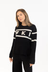Close-up of SKI graphic on black knit sweater with ribbed cuffs

