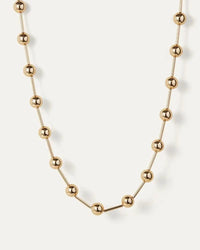 Gold Celeste Necklace by Jenny Bird, laid flat on white background, showcasing high-polish finish and luminous spheres.